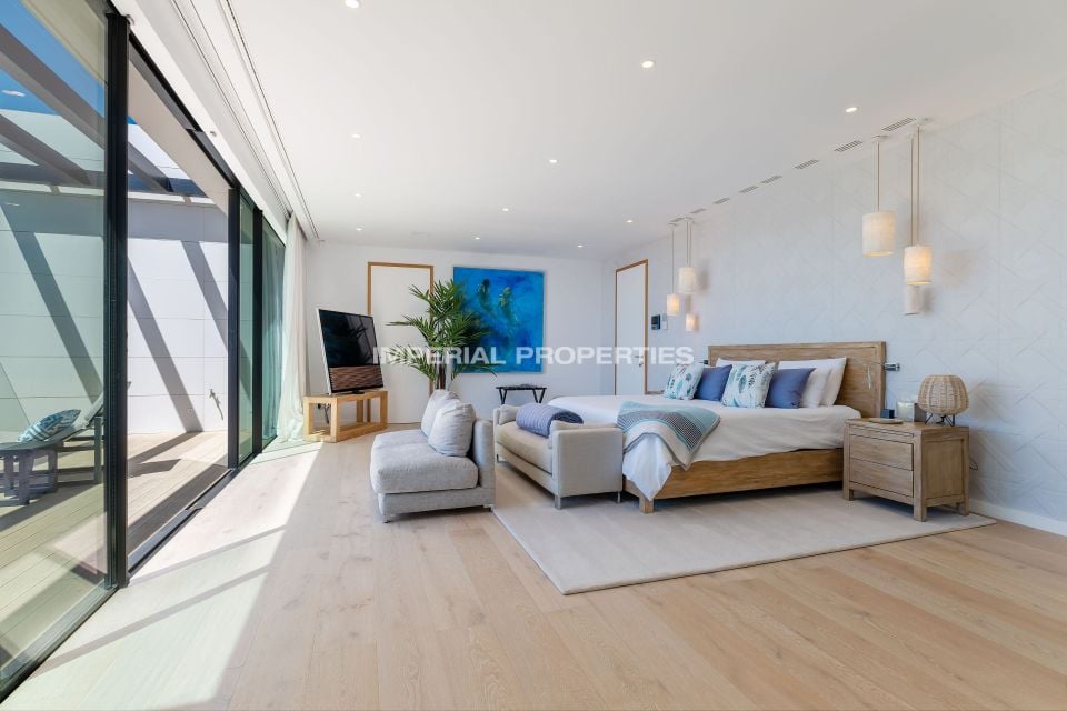 Bedroom with a wood headboard, blue artwork and glass doors to a terrace