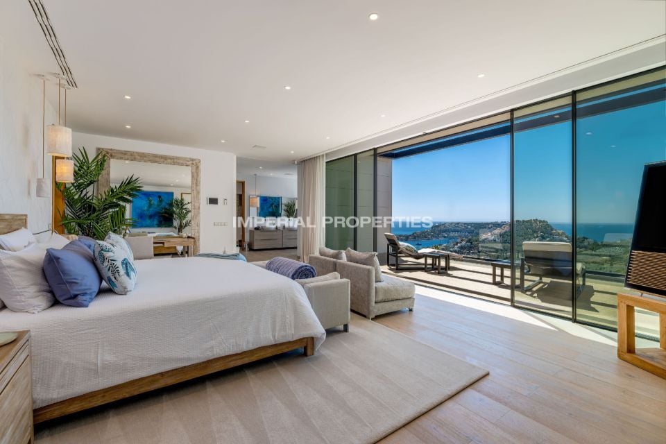 Bedroom with a wood bed, glass wall and a view of the bay