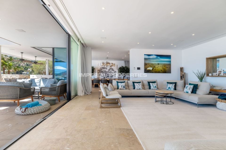 Living room with a beige sectional, round wood tables and doors open to the terrace