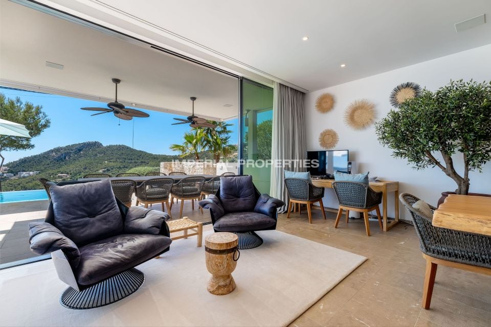 Open living room looking through glass doors to a covered dining terrace and the pool