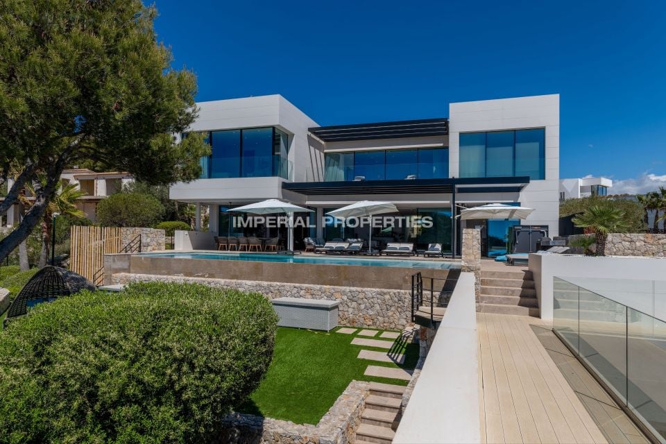 White villa elevation with an outdoor swimming pool, loungers and stone terraces