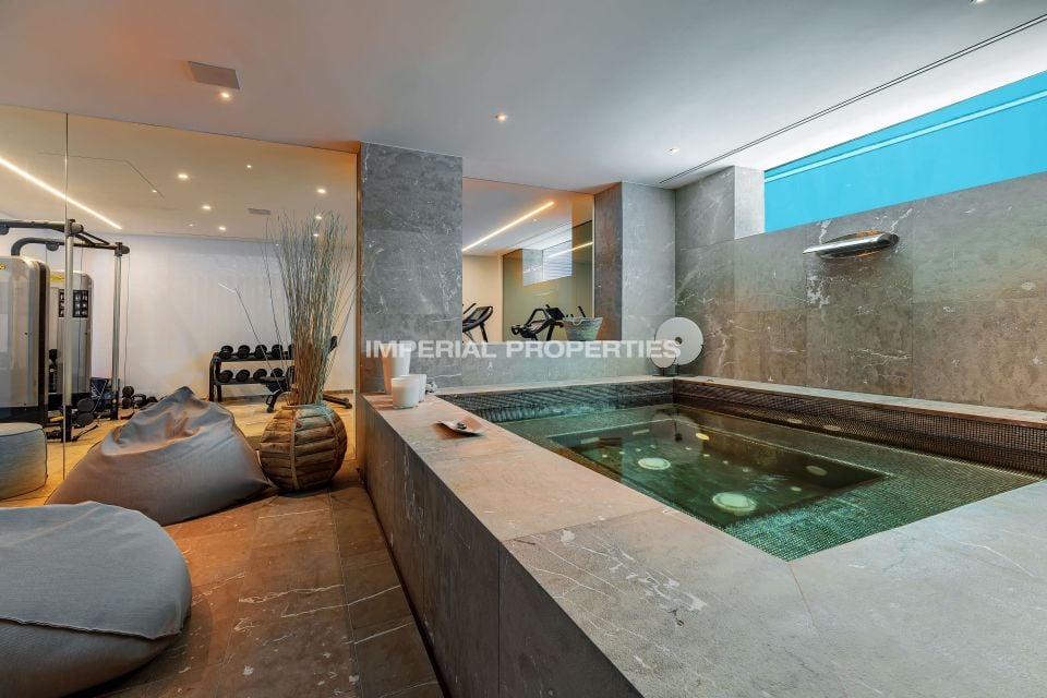 Indoor spa pool beside a gym with weights and an exercise bike